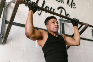 Athletic man doing pull-ups in a gym setting, showcasing strength and fitness.