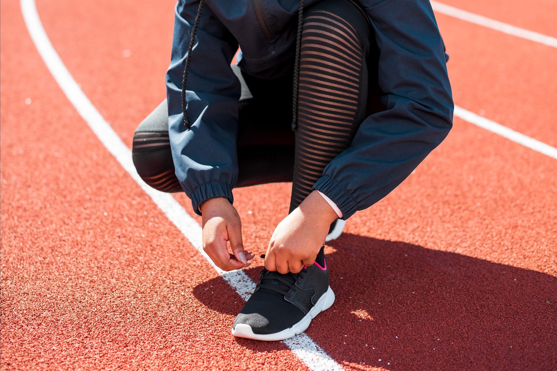 Close-up of an athlete tying sneakers on a track during the day. Perfect fit concept.